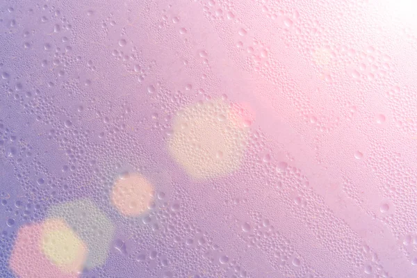 Background texture wet pink glass with drops in the sun and lens