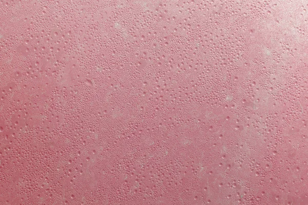 Background texture wet pink glass with drops in the sun and lens
