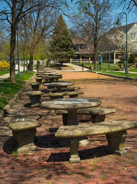 オハイオの村のコモンズの隣にある古いレンガ造りの通りを占める石のテーブルの列 各テーブルの表面に描かれたチェスやチェッカーのためのチェッカーボードがあります — ストック写真