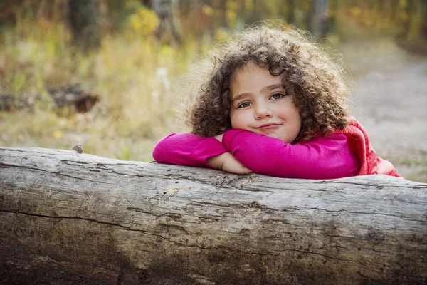 Na floresta de outono pequena menina engraçada encaracolado . — Fotografia de Stock