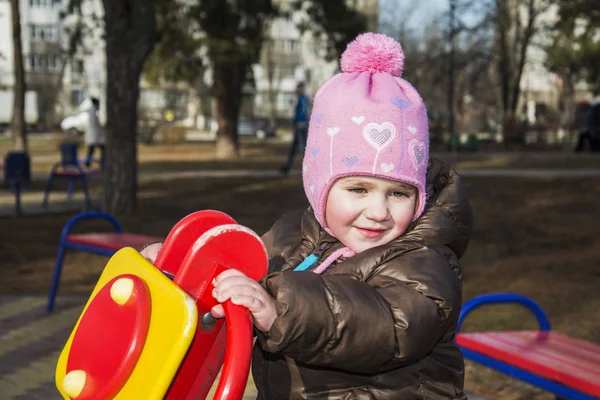 Весной на детской площадке улыбается маленькая девочка . — стоковое фото