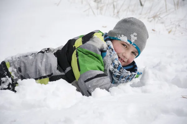 V zimě zasněžené borovice lesní chlapec leží závěji. — Stock fotografie