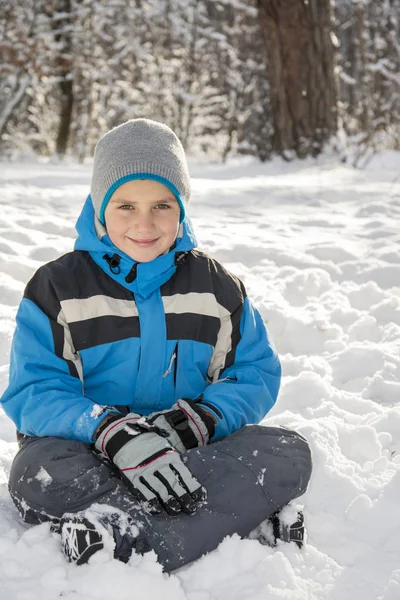 In winter, snow-covered pine forest boy lies near the snowdrift. — Stock Photo, Image