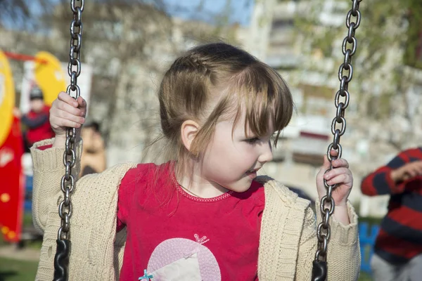 Summer bright sunny day little girl riding on a swing. Royalty Free Stock Images