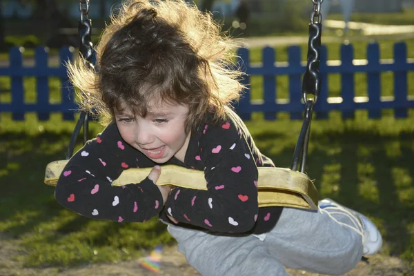 In the evening in the park on the playground girl riding on a sw — Stock Photo, Image