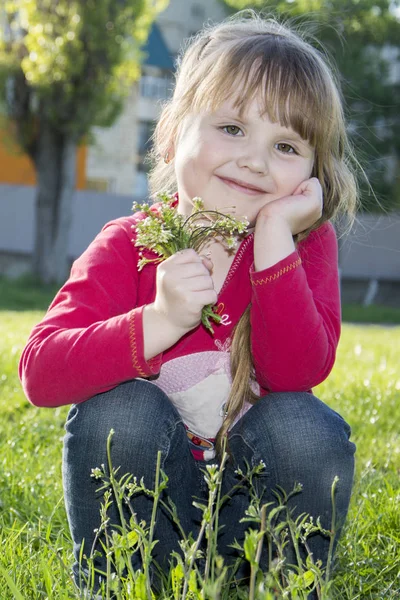 Frühling im Park schöne kleine Mädchen auf dem Gras sitzen wi — Stockfoto