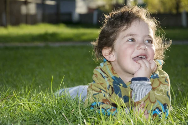 Primavera en el parque en la hierba es una niña divertida . —  Fotos de Stock