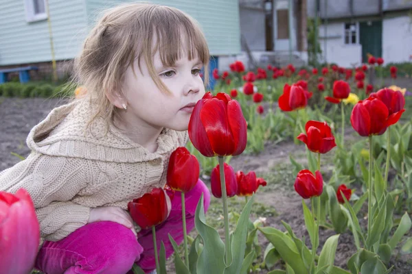 Весна в саду красивой маленькой девочки сидит и нюхает — стоковое фото