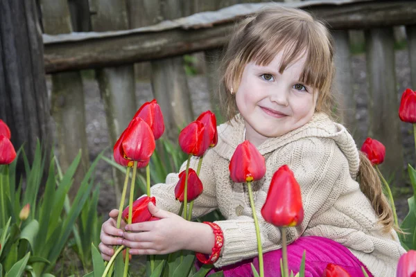 Spring in the garden of a beautiful little girl sitting near tul — Stock Photo, Image