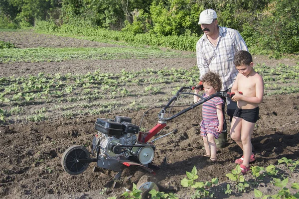 Frühling im Garten Mann pflügt Land Motor-Block kleiner Sohn und — Stockfoto