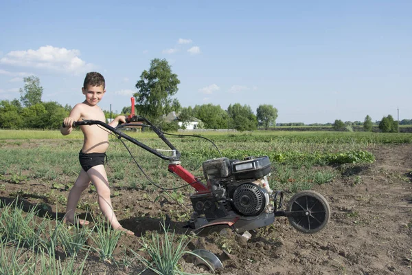 Primavera en el jardín un niño pequeño arando el suelo el motor-b — Foto de Stock