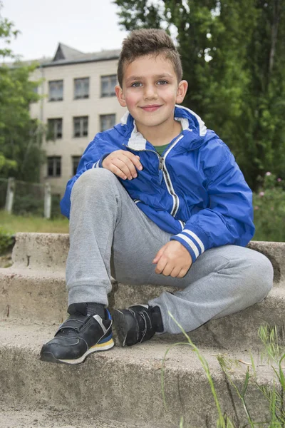 Sommer auf dem Schulhof auf den Stufen lächelnder Junge. — Stockfoto