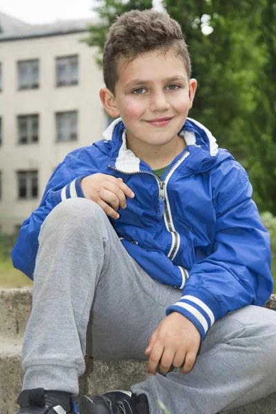 Estate nel cortile della scuola seduto sui gradini sorridente ragazzo . — Foto Stock