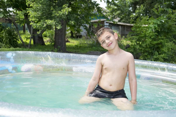 Το καλοκαίρι ο κήπος αγόρι λούζει με Φουσκωτή πισίνα. — Φωτογραφία Αρχείου