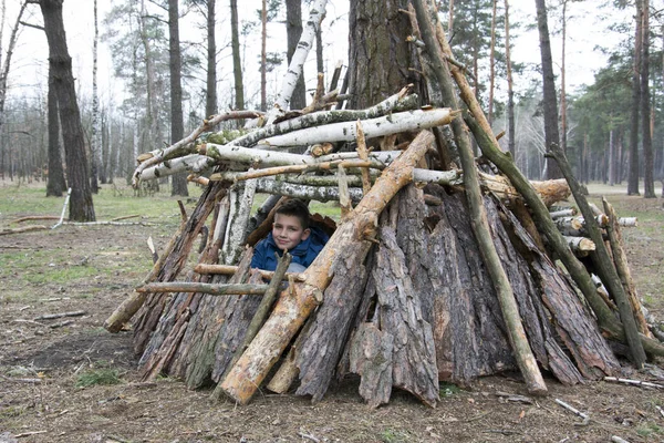 Im Frühling baute der Junge in einem Kiefernwald eine Hütte aus Stöcken. — Stockfoto