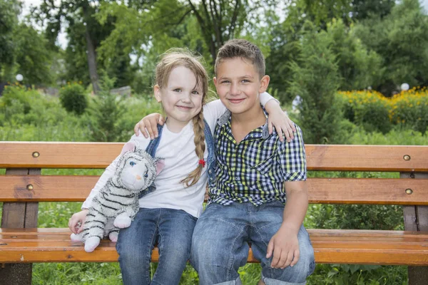 Im Sommer im Park umarmt ein kleiner Junge das Mädchen. — Stockfoto