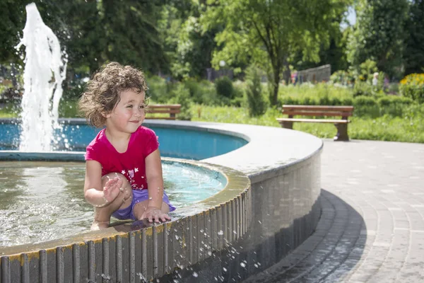 In de zomer, gir spelen in de fontein in het park. — Stockfoto