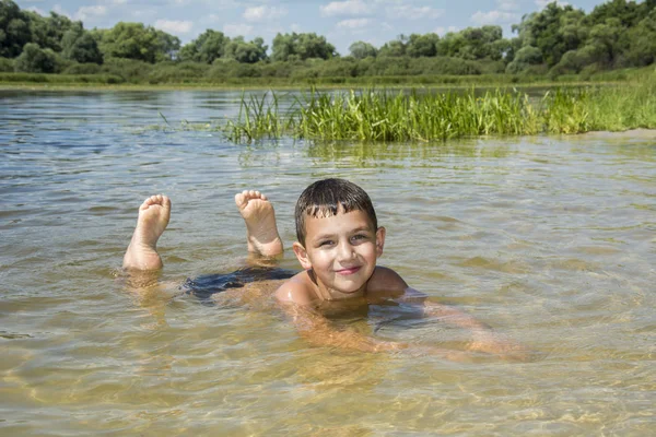 No verão, em um dia brilhante e ensolarado, o menino jaz na areia em t — Fotografia de Stock