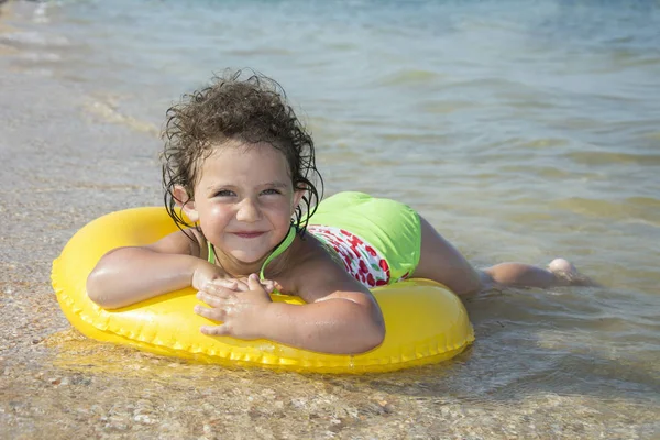 V létě, jasný a slunečný den u moře, malá kudrnatá holka — Stock fotografie