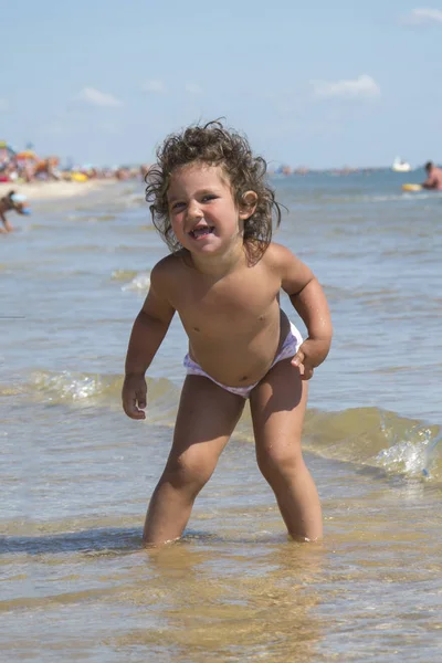 No verão, na praia junto ao mar, uma menina dança no — Fotografia de Stock