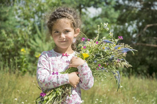 Im Sommer gibt es ein kleines süßes Mädchen mit einem Strauß Wildblumen — Stockfoto
