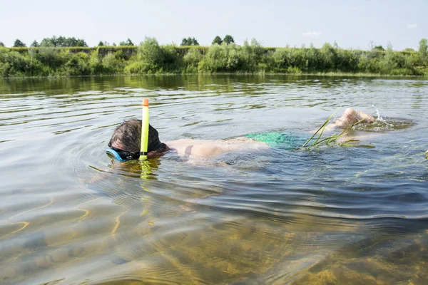 En verano, un hombre con una máscara y un tubo en agua clara nadan a lo largo de —  Fotos de Stock