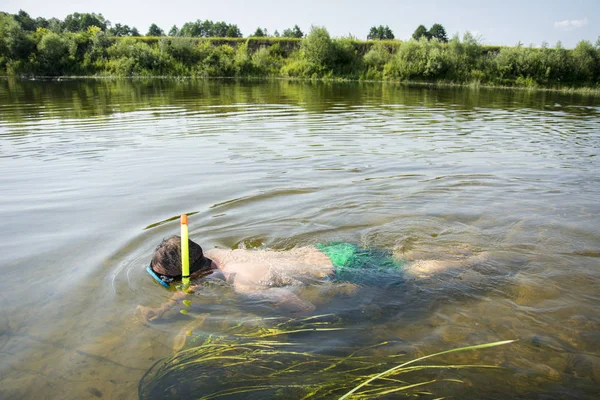 In summer, a man in a mask and a tube in clear water swim along — Stock Photo, Image
