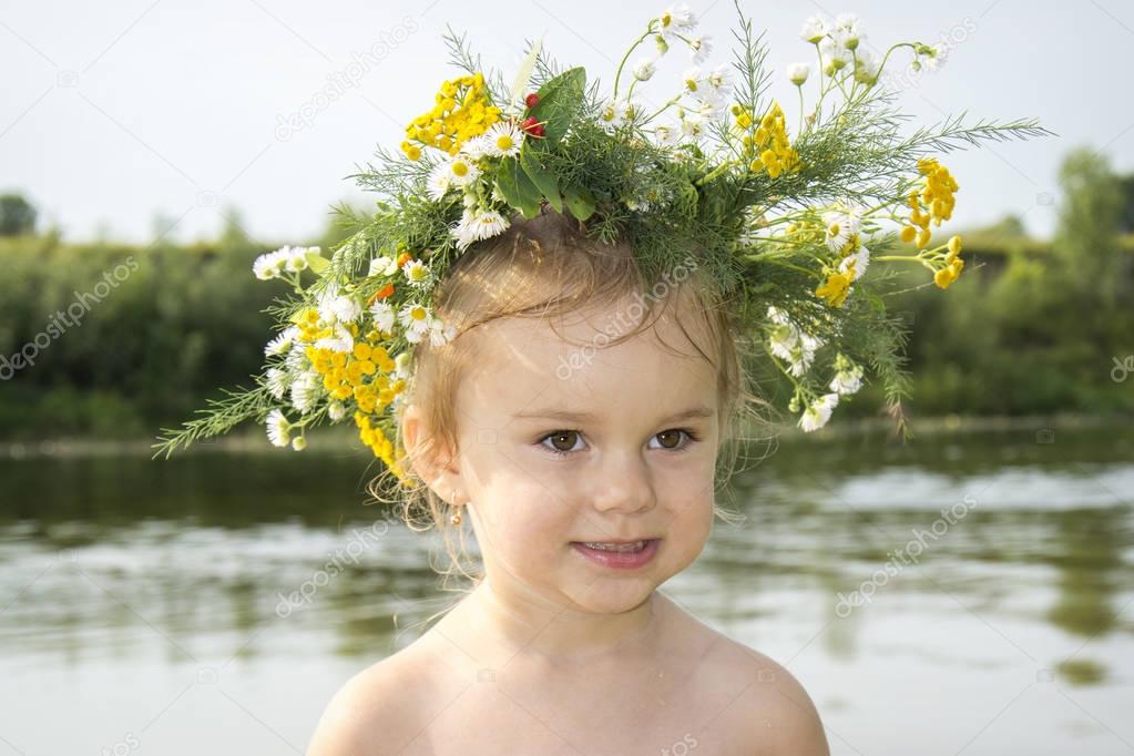 In the summer near the river there is a little beautiful girl in