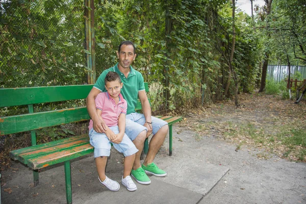 Summer in the street on the bench is a son with his father. — Stock Photo, Image