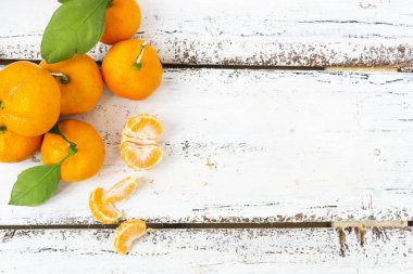 Büyük bir mandalina kütlesi beyaz ahşap bir arka planda yatar. Dilimlenmiş bir sıra mandalina yalanlar. Noel konsepti.