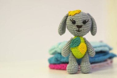 Gri örülü oyuncak köpek - örgü renkli giysiler içinde - açık arkaplanda renkli amigurumi oyuncağı. Uzayı kopyala Hobi konsepti.