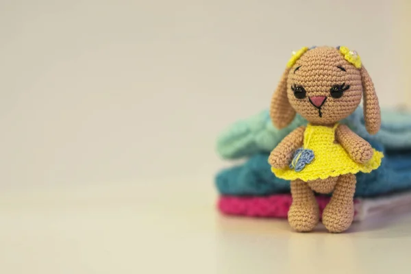 Knitted doll hare and knitted in yellow clothes - colored toy amigurumi on a light background. Copy space. needlework concept. — Stock Photo, Image