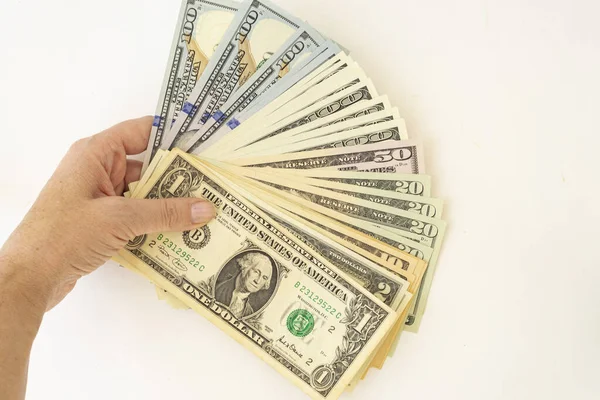 A female hand holds several hundred dollar bills spread out in a fan on a white background. There is a place for text