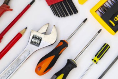 İnşaat araçları beyaz arka planda yatar. Tornavida, testere, gaz anahtarı, kalem, kerpeten, desen olarak yalan söyleyen bir tornavida. İnşaat konsepti, ev onarımı..