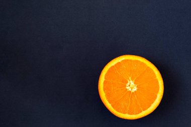 Siyah arka planda taze dilimlenmiş portakal var. Tebeşir tahtasında tropik meyveler. Boşluğu kopyala