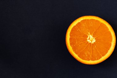 Siyah arka planda taze dilimlenmiş portakal var. Tebeşir tahtasında tropik meyveler. Boşluğu kopyala
