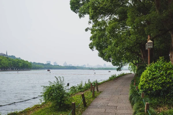Percorso tra gli alberi in parco presso West Lake, Hangzhou, Cina — Foto Stock