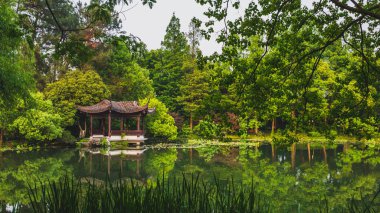 Traditional Chinese architecture by water in park by West Lake, 