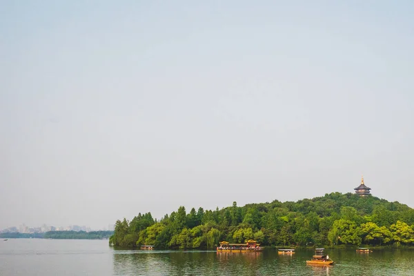 Barcos sobre el agua con la pagoda Leifeng sobre la colina, en West Lake, Ha — Foto de Stock