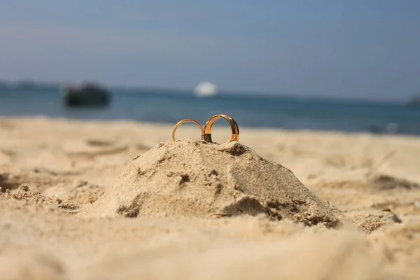 Свадебные кольца лежат на песчаном замке — стоковое фото