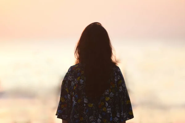 Rückansicht einer jungen Mädchensilhouette, die steht und die Sonne beobachtet Stockbild