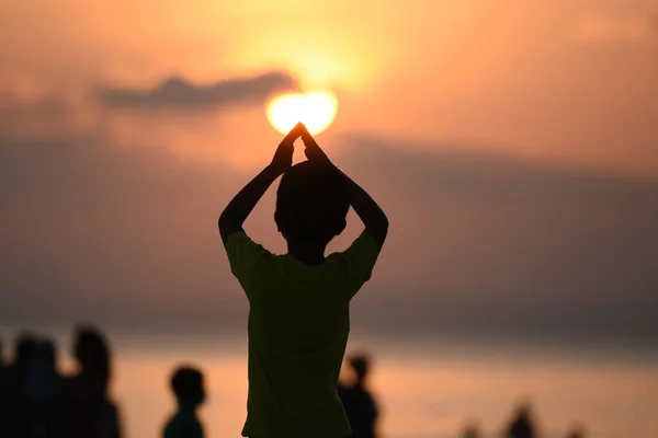 Vista posterior de una silueta de niño joven de pie y y haciendo forma — Foto de Stock