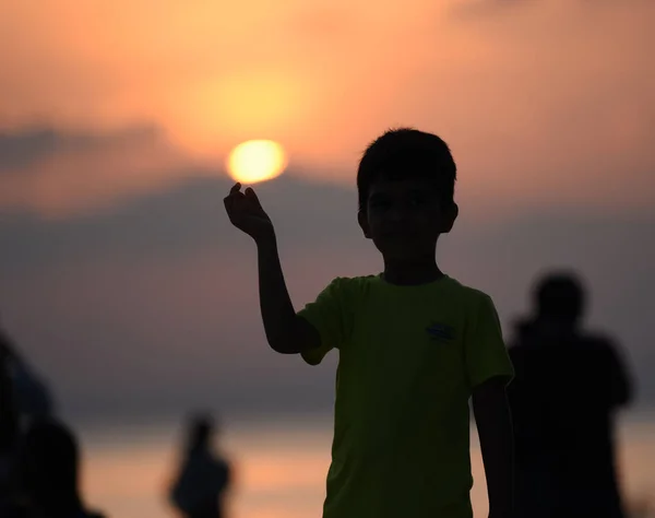 Silhouette image of young boy holding sun — Stock Photo, Image