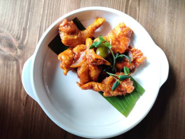 Kızarmış tavuk kanatları beyaz tabakta servis edilir.