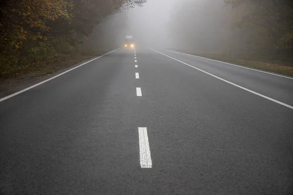 Car on the road in the fog. Autumn landscape. — Stock Photo, Image