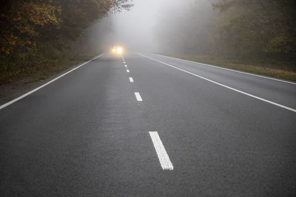 Car on the road in the fog. Autumn landscape. — Stock Photo, Image