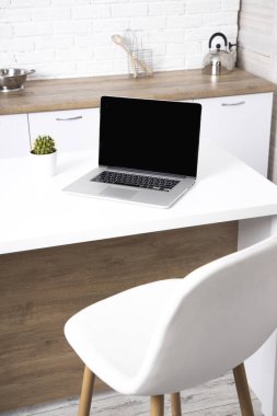 Beyaz bir masada fareyle birlikte boş ekranı olan bir laptop. Eve.