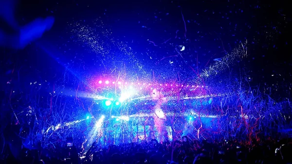 Crowd of people being showered in streamers and confetti at a rock concert Stock Photo