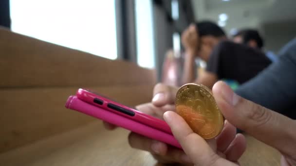 Χρησιμοποιώντας Ένα Smartphone Ένα Χέρι Και Κρατώντας Ένα Νόμισμα Bitcoin — Αρχείο Βίντεο