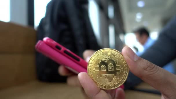Använda Smartphone Med Hand Och Hålla Ett Bitcoin Mynt — Stockvideo